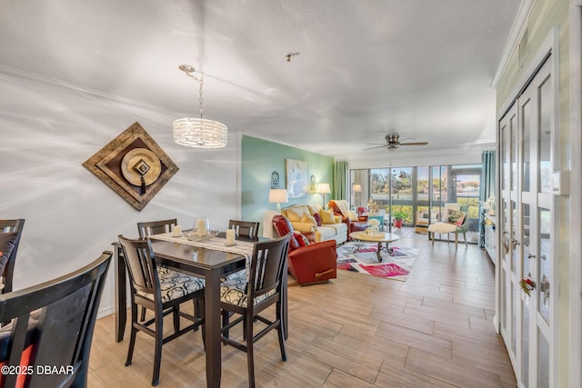 456 Bouchelle Dr Unit 104, New Smyrna Beach, FL 32169 - dining area with light wood finished floors, ceiling fan with notable chandelier, a textured ceiling, and crown molding