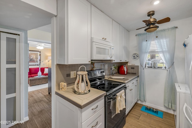 456 Bouchelle Dr Unit 104, New Smyrna Beach, FL 32169 - kitchen with decorative backsplash, white microwave, black range with electric stovetop, and ceiling fan