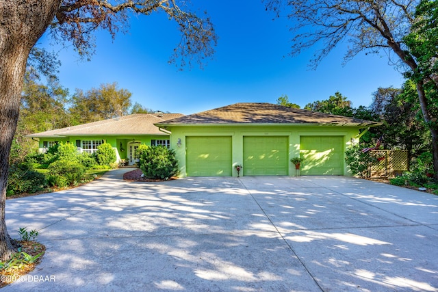 ranch-style home featuring a garage, concrete driveway, and stucco siding