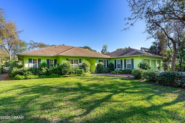 ranch-style home with stucco siding, an attached garage, and a front yard