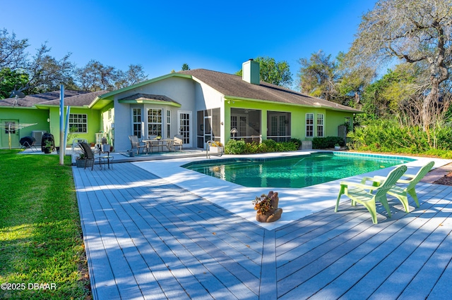 outdoor pool featuring a lawn and a deck