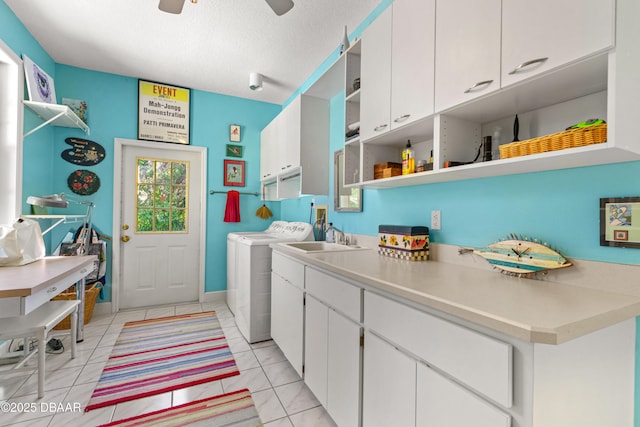 laundry area featuring washing machine and clothes dryer, cabinet space, a textured ceiling, a ceiling fan, and a sink