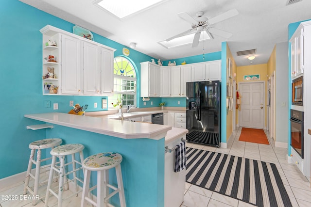 kitchen featuring visible vents, a peninsula, a skylight, open shelves, and black appliances