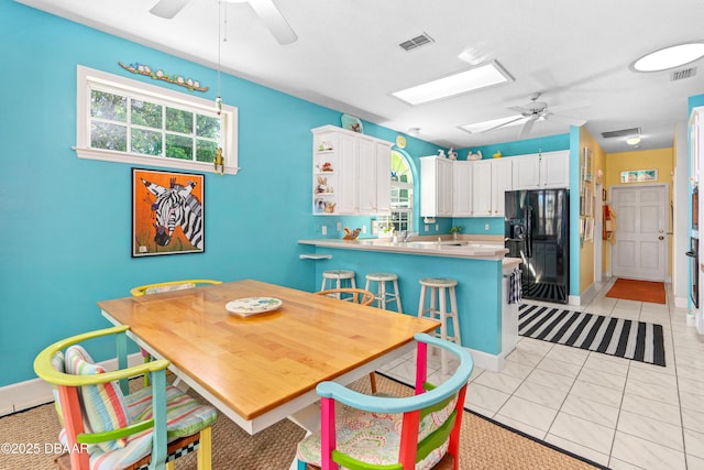 dining room with light tile patterned floors, visible vents, a skylight, and ceiling fan