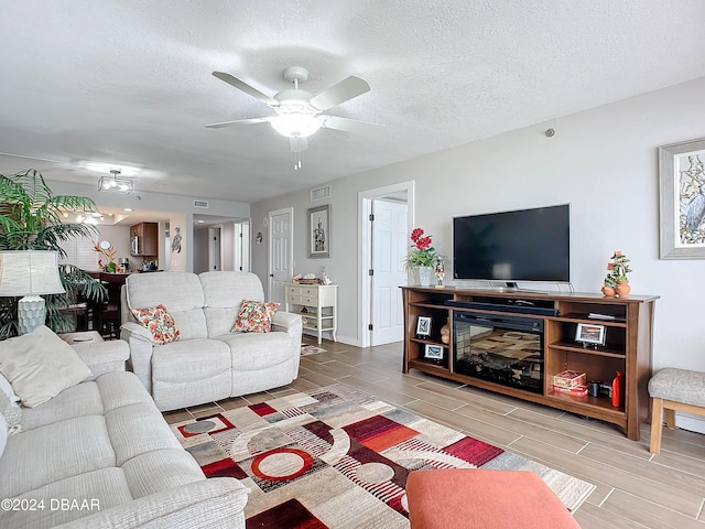 living room with ceiling fan and a textured ceiling