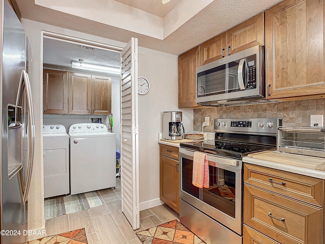 kitchen featuring light wood-type flooring, independent washer and dryer, backsplash, and appliances with stainless steel finishes