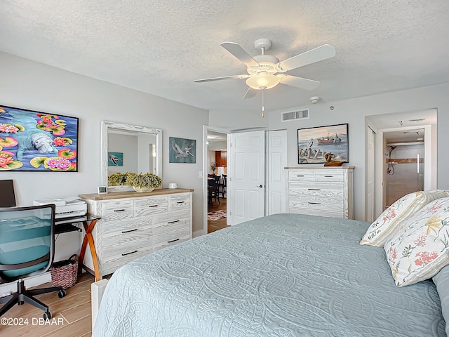 bedroom with ceiling fan, light wood-type flooring, and a textured ceiling