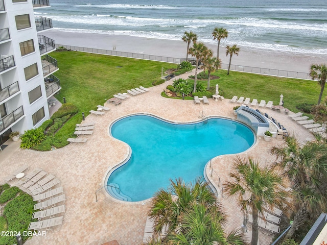 view of pool with a lawn, a water view, and a beach view