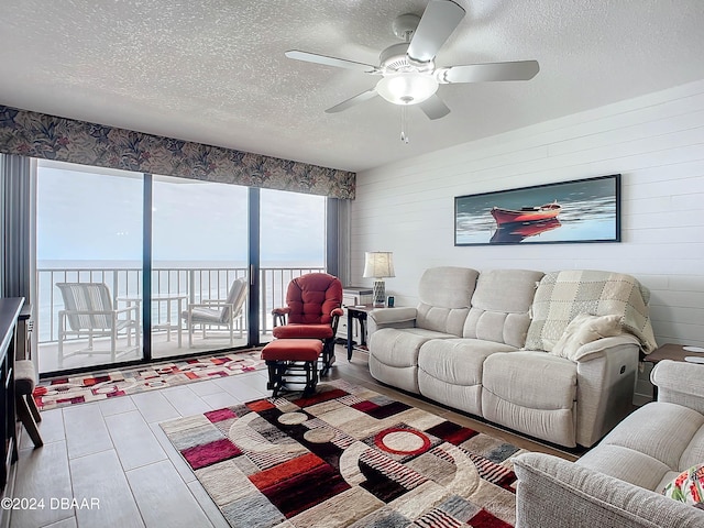 living room with ceiling fan, a water view, and a textured ceiling