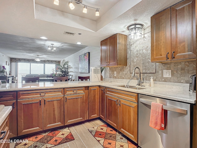 kitchen with sink, tasteful backsplash, stainless steel dishwasher, a textured ceiling, and light wood-type flooring