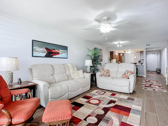 living room with wood-type flooring, a textured ceiling, and ceiling fan