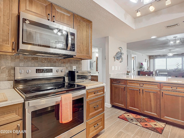 2425 S Atlantic Ave Unit 1004, Daytona Beach Shores, FL 32118 - kitchen with appliances with stainless steel finishes, brown cabinets, light countertops, and decorative backsplash