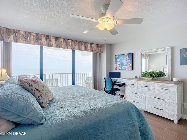 bedroom featuring access to exterior, ceiling fan, dark hardwood / wood-style flooring, and a textured ceiling