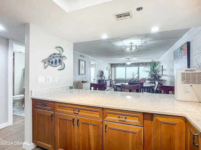 2425 S Atlantic Ave Unit 1004, Daytona Beach Shores, FL 32118 - kitchen with a peninsula, brown cabinets, light stone countertops, open floor plan, and recessed lighting