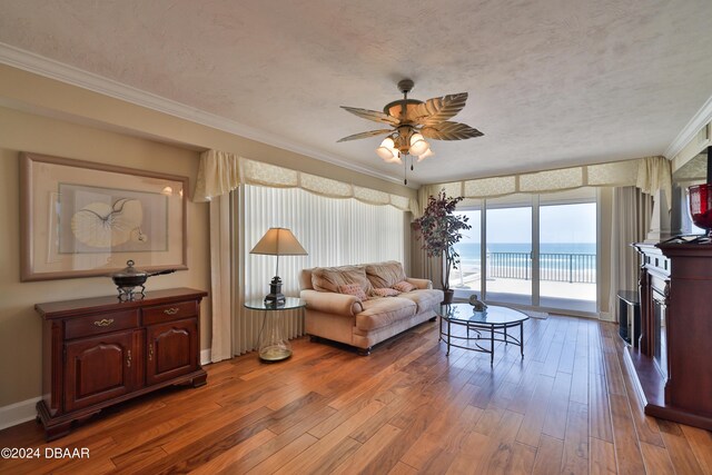 4631 S Atlantic Ave Unit 8101, Ponce Inlet, FL 32127 - living room featuring wood-type flooring, crown molding, ceiling fan, a fireplace, and a textured ceiling