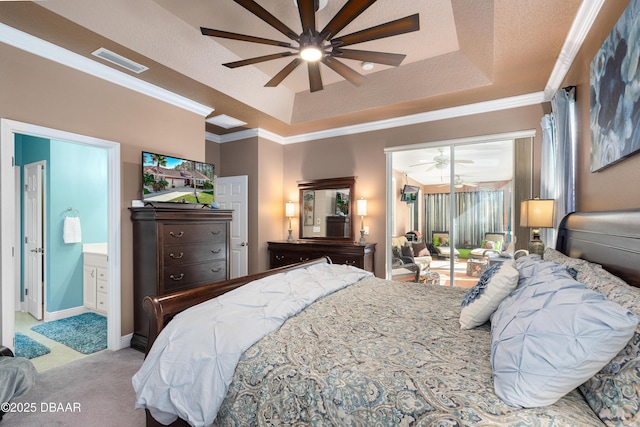 carpeted bedroom with ornamental molding, a tray ceiling, and ensuite bathroom