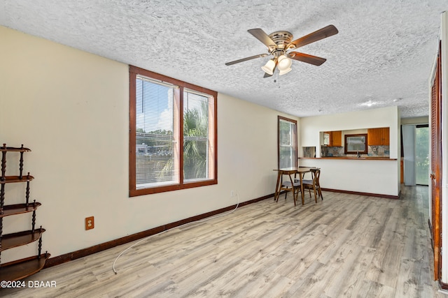 living room with light wood-type flooring, a wealth of natural light, a textured ceiling, and ceiling fan