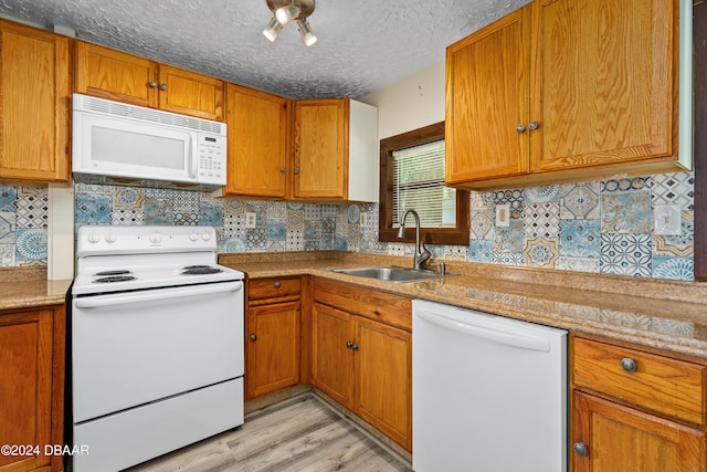 kitchen with sink, tasteful backsplash, a textured ceiling, white appliances, and light hardwood / wood-style flooring