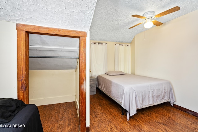 bedroom featuring dark wood-type flooring, ceiling fan, a textured ceiling, and vaulted ceiling