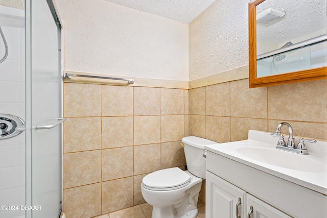 bathroom with tile walls, vanity, a textured ceiling, an enclosed shower, and toilet