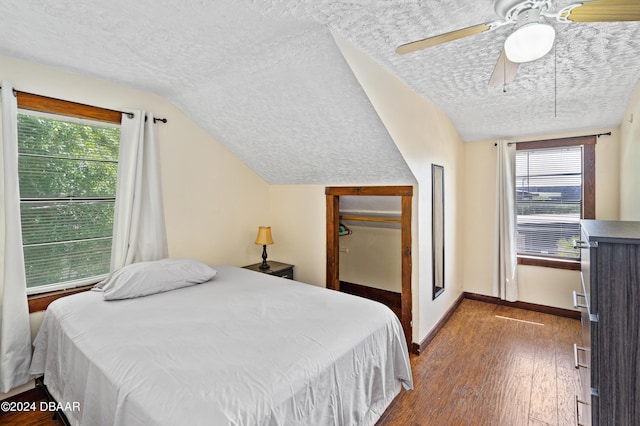 bedroom featuring multiple windows, wood-type flooring, a textured ceiling, and lofted ceiling