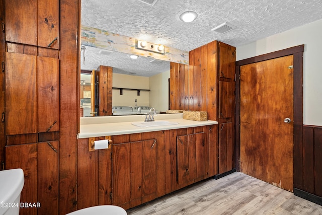 bathroom featuring wood-type flooring, a textured ceiling, and wooden walls