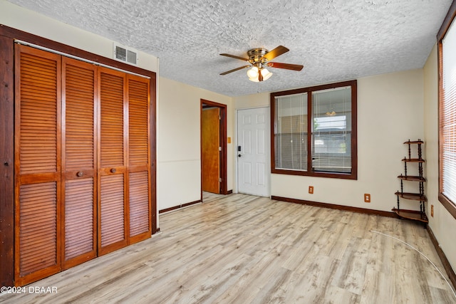 unfurnished bedroom with light wood-type flooring, multiple windows, a textured ceiling, and ceiling fan