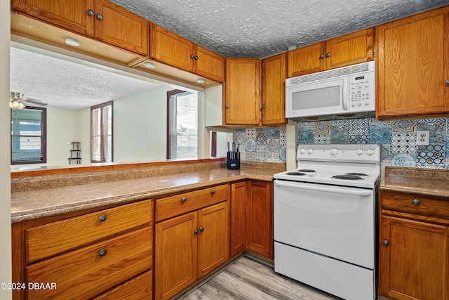 kitchen with tasteful backsplash, white appliances, a textured ceiling, and light hardwood / wood-style floors