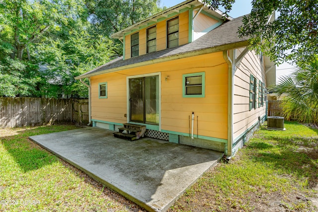 back of house featuring central AC unit, a lawn, and a patio area