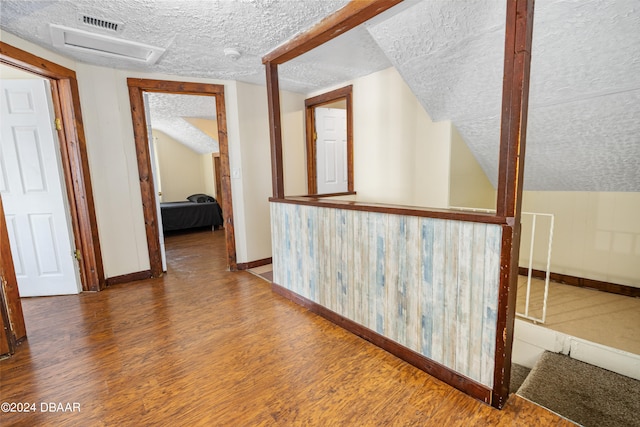 corridor with wood-type flooring and a textured ceiling