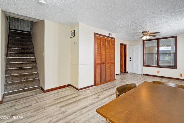 unfurnished dining area with ceiling fan, a textured ceiling, and light hardwood / wood-style flooring