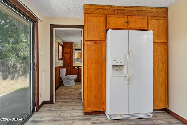 kitchen with white fridge with ice dispenser, a textured ceiling, and light hardwood / wood-style flooring