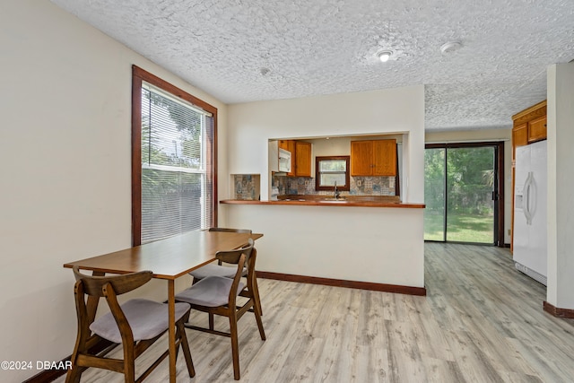 dining space featuring a textured ceiling and light hardwood / wood-style floors