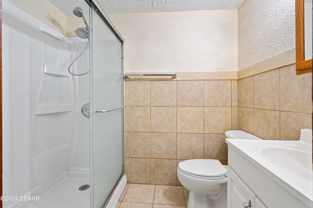 bathroom featuring tile walls, tile patterned floors, a textured ceiling, toilet, and a shower with shower door