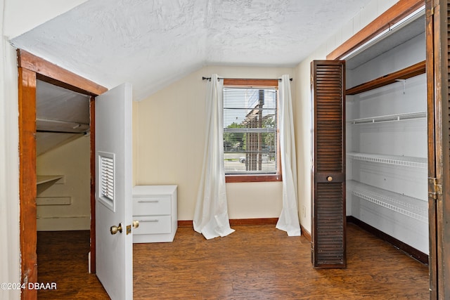 unfurnished bedroom with a textured ceiling, dark hardwood / wood-style floors, vaulted ceiling, and a closet