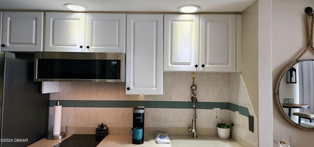 2700 N Atlantic Ave Unit 905, Daytona Beach, FL 32118 - detailed view of stainless steel microwave, backsplash, and white cabinetry