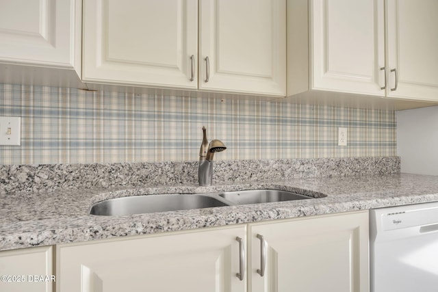 kitchen with light stone countertops, dishwasher, a sink, and backsplash