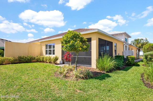 914 Attitude Ave, Daytona Beach, FL 32124 - view of side of home with stucco siding, a sunroom, and a lawn