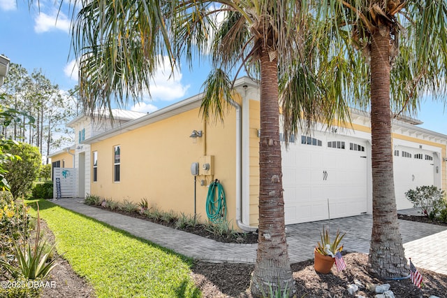914 Attitude Ave, Daytona Beach, FL 32124 - view of side of home with stucco siding, an attached garage, and decorative driveway