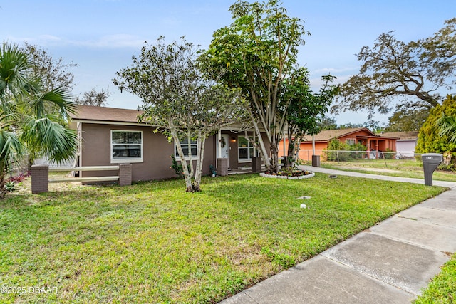 ranch-style home with fence, a front lawn, and stucco siding