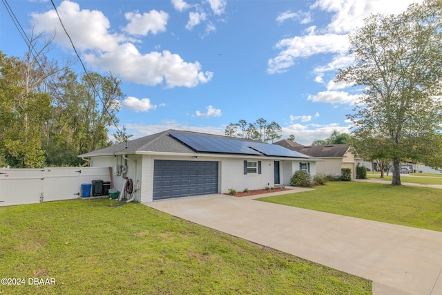 single story home with a garage, solar panels, and a front lawn