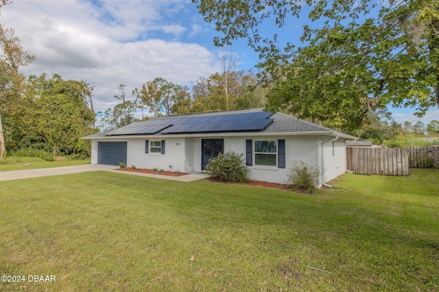 single story home featuring a garage, solar panels, and a front yard