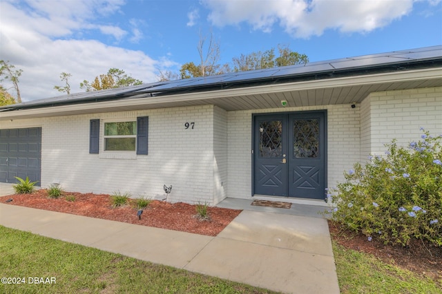 view of exterior entry featuring a garage and solar panels