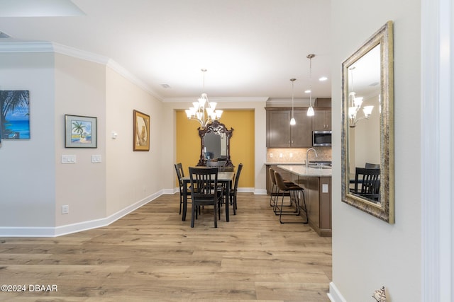 dining space featuring light hardwood / wood-style floors, ornamental molding, and an inviting chandelier