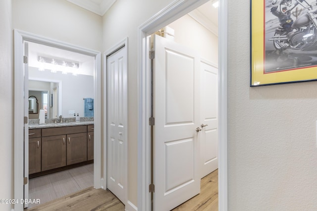 corridor featuring ornamental molding, sink, and light hardwood / wood-style flooring