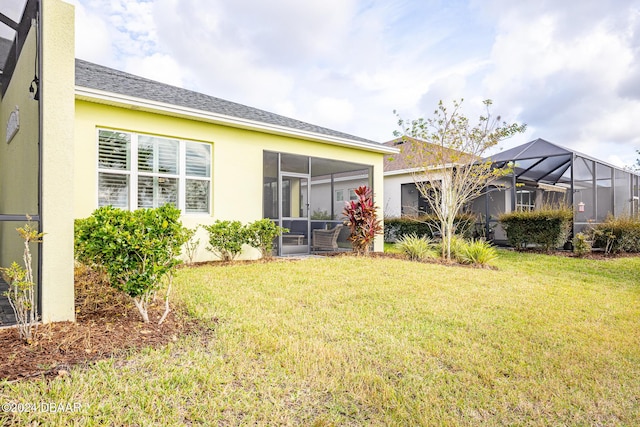 rear view of property featuring a lawn and glass enclosure