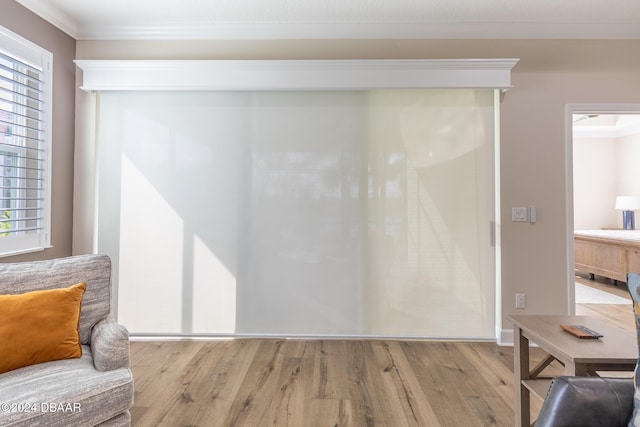 living area with crown molding, a healthy amount of sunlight, and light hardwood / wood-style floors