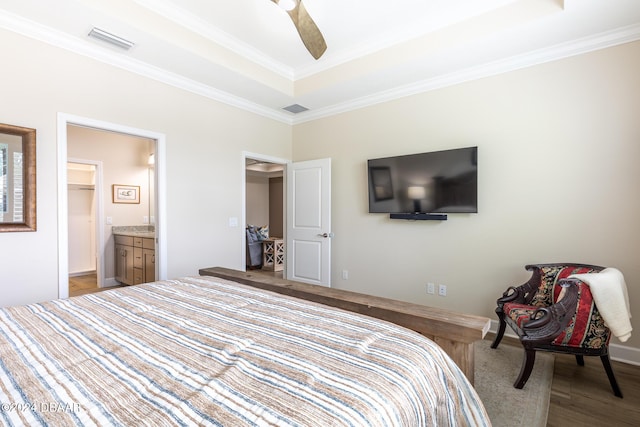 bedroom featuring ensuite bathroom, ceiling fan, light wood-type flooring, ornamental molding, and a tray ceiling