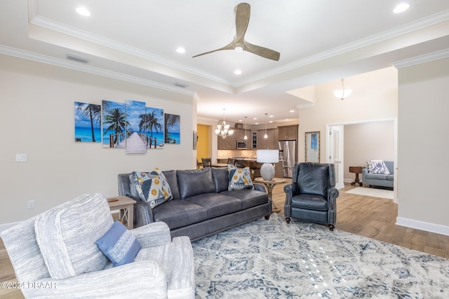 living room featuring ceiling fan with notable chandelier, light hardwood / wood-style floors, and ornamental molding