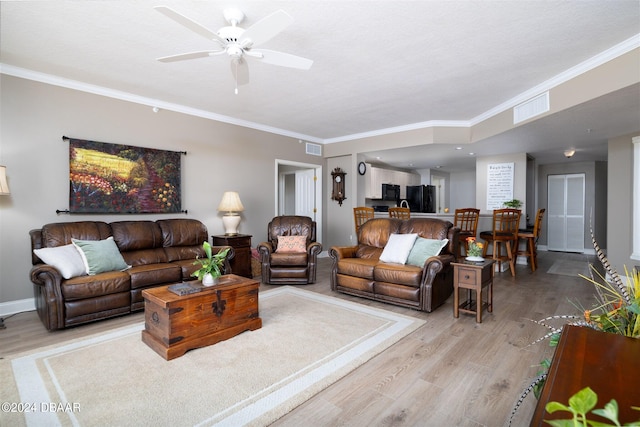 living room with ceiling fan, a textured ceiling, light wood-type flooring, and ornamental molding